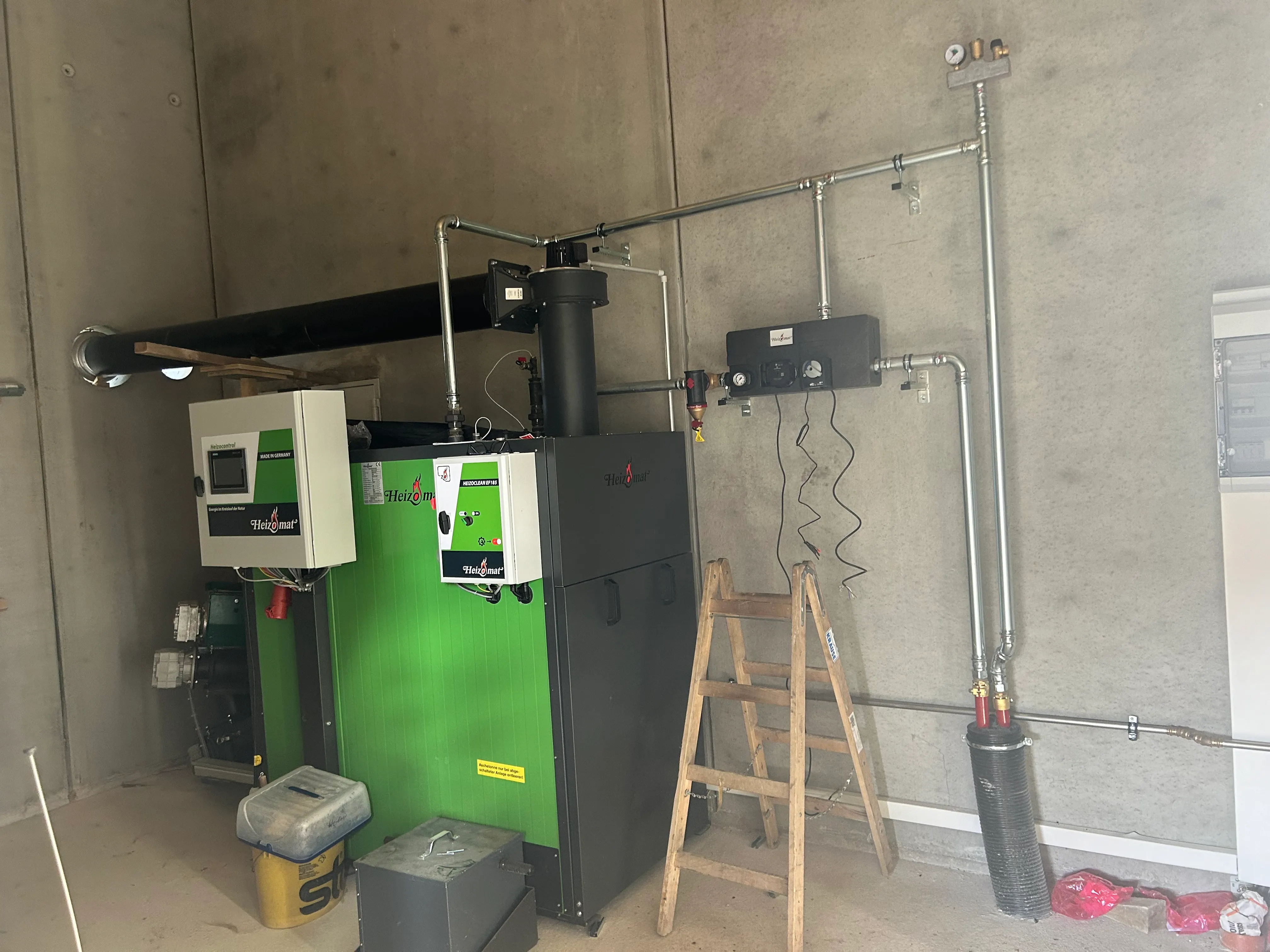 Installierter Hackschnitzelkessel mit Steuerung und Saugaustragung im Heizraum — eigene Anlage von Häusler Haustechnik.